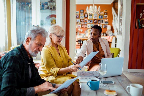 Two people signing paperwork at a table with a businessperson.