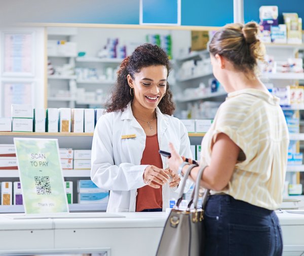 Adult pays for medication at a pharmacy counter.