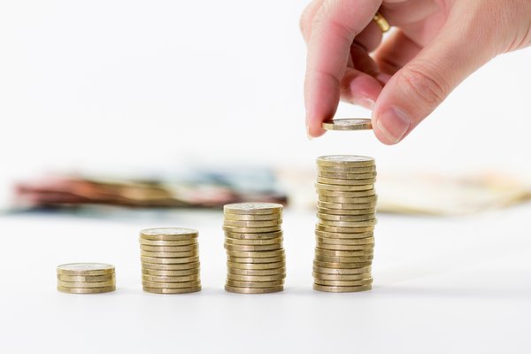 Hand adding a coin to a stack of coins.