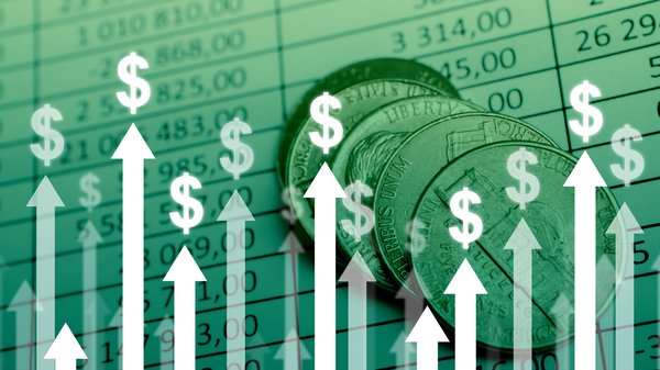 Arrows in a bar graph, pointing upward, topped with dollar signs and with coins and charts in the background.