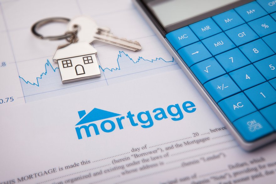 Housekeys and a calculator sitting atop a mortgage contract.