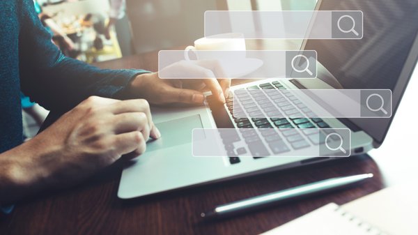 Search engine boxes superimposed over background image of a person typing on laptop.