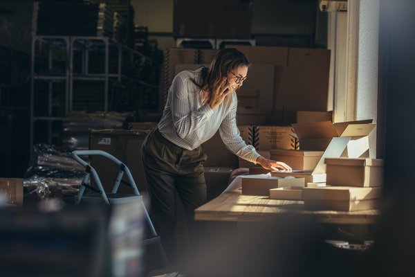 Entrepreneur surrounded by packages while taking inventory in a storage room.