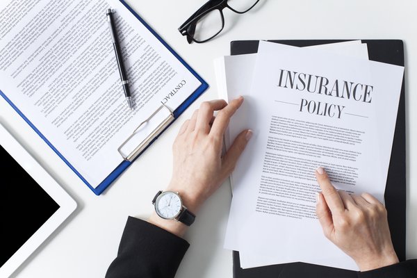 Person reading through an insurance policy lying on a desk.