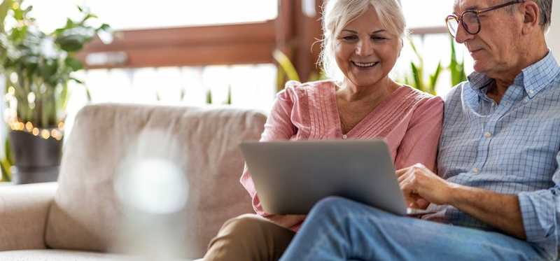 Adult couple smiling while looking at laptop at home.