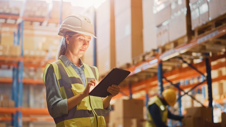 Person standing in warehouse and holding a tablet.